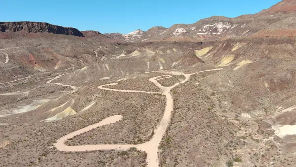 a view of a dry yard with mountains in the background