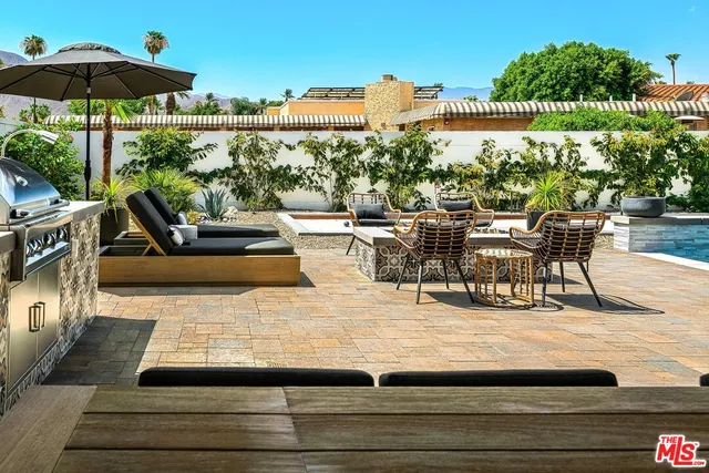 a view of a patio with couches table and chairs under an umbrella with a fireplace