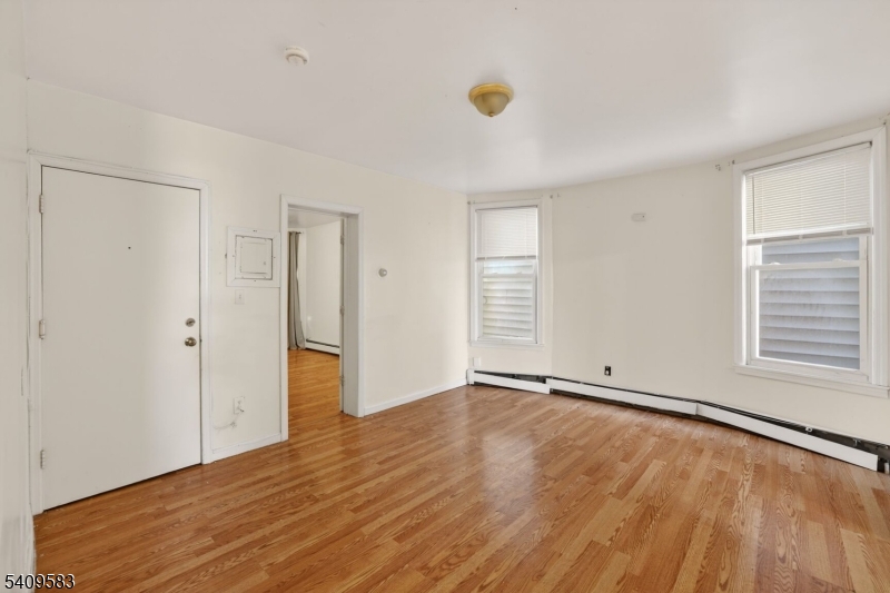 186 3rd Street, Unit 1 Newark, NJ 07107 - Photo 11 of 25 an empty room with wooden floor and windows
