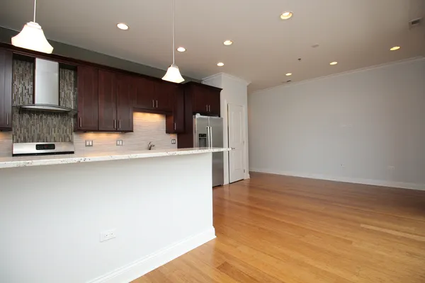 a large kitchen with stainless steel appliances a large counter top a stove and a refrigerator with wooden floor