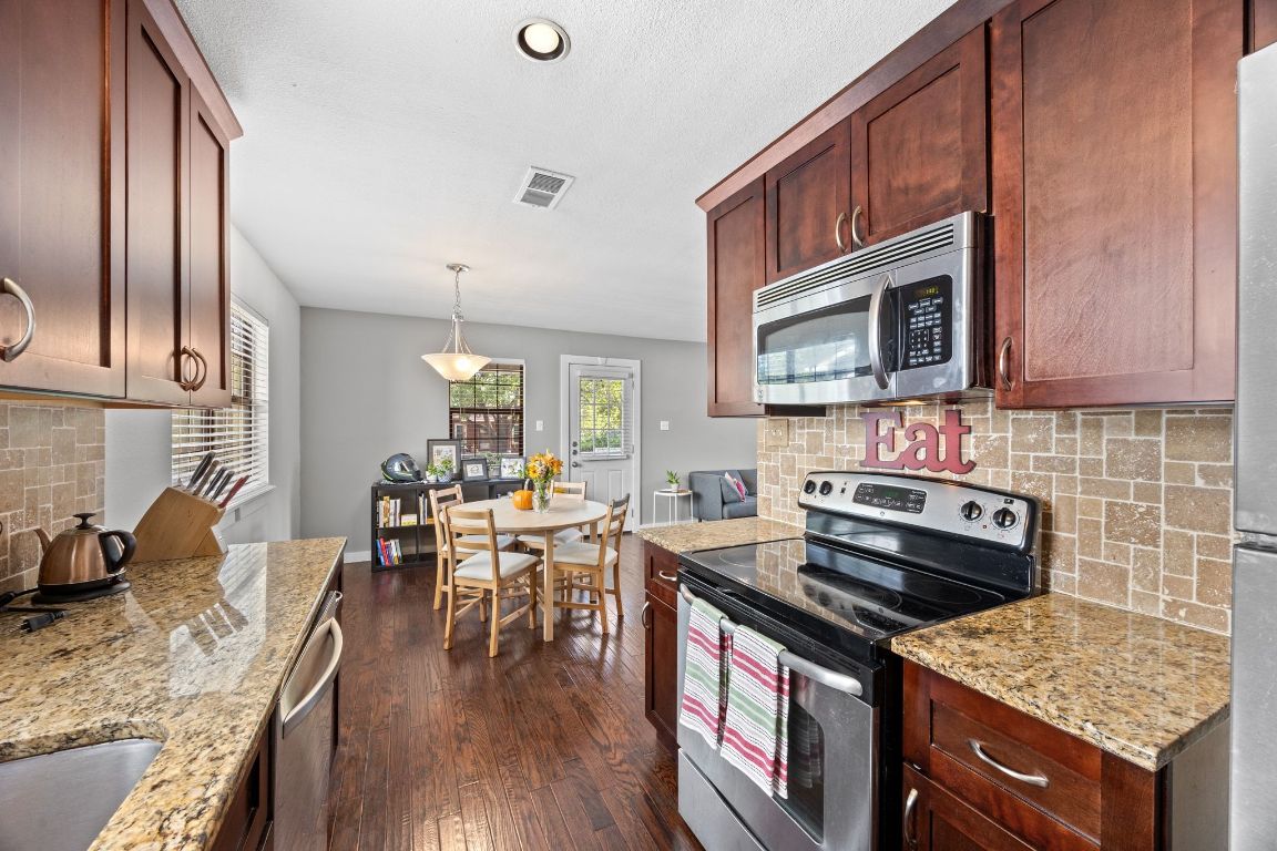 5500 Evans Avenue Austin, TX 78751 - Photo 16 of 27 a kitchen with granite countertop a stove top oven a sink dishwasher a dining table and chairs with wooden floor