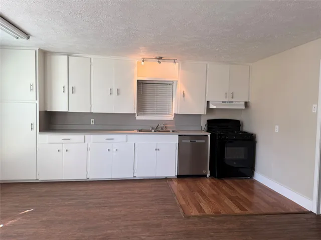a kitchen with granite countertop white cabinets and black stainless steel appliances