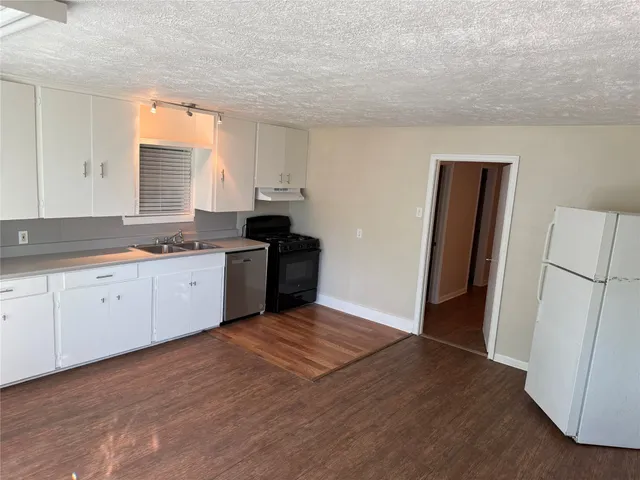 a kitchen with granite countertop a refrigerator sink and cabinets