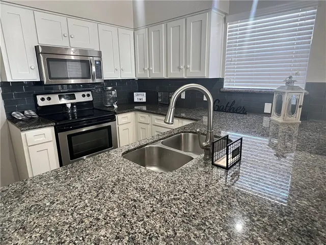 a kitchen with stainless steel appliances granite countertop a sink and a stove