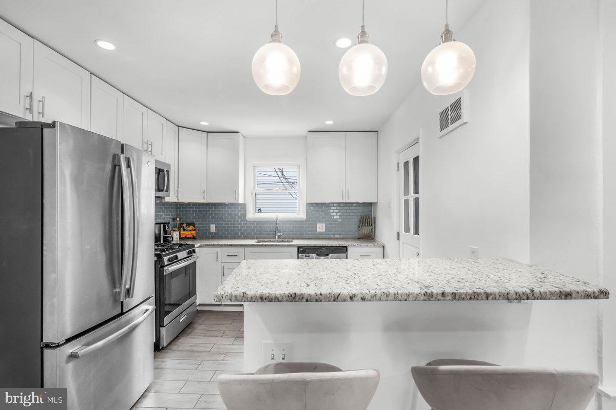 7734 Temple Road Philadelphia, PA 19150 - Photo 5 of 33 a kitchen with stainless steel appliances granite countertop a sink refrigerator stove and microwave