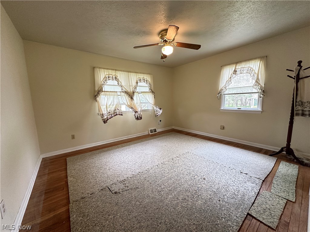 2408 Brown Road Ashtabula, OH 44004 - Photo 12 of 27 Empty room featuring dark hardwood / wood-style floors, ceiling fan, and a textured ceiling