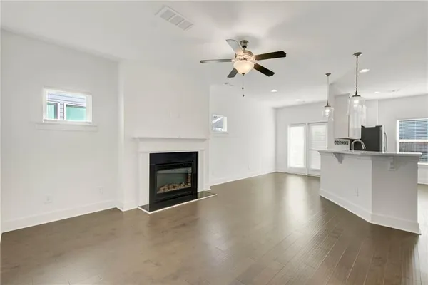 a view of an empty room with kitchen and a fireplace