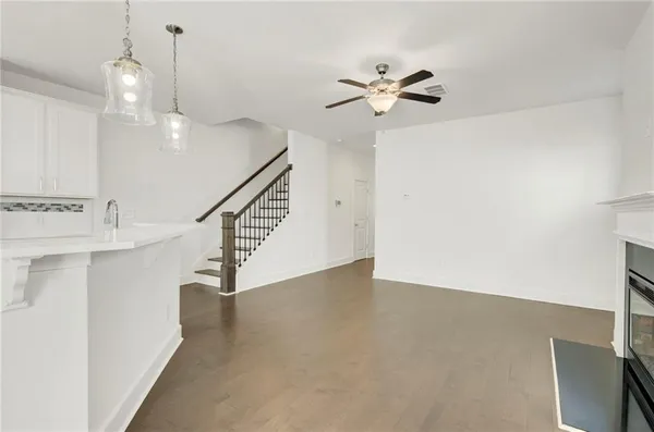 a view of an empty room with wooden floor and a chandelier