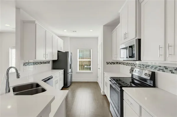 a kitchen with granite countertop a sink stove and refrigerator