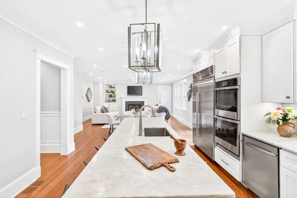 a living room with stainless steel appliances furniture a rug kitchen view and a chandelier