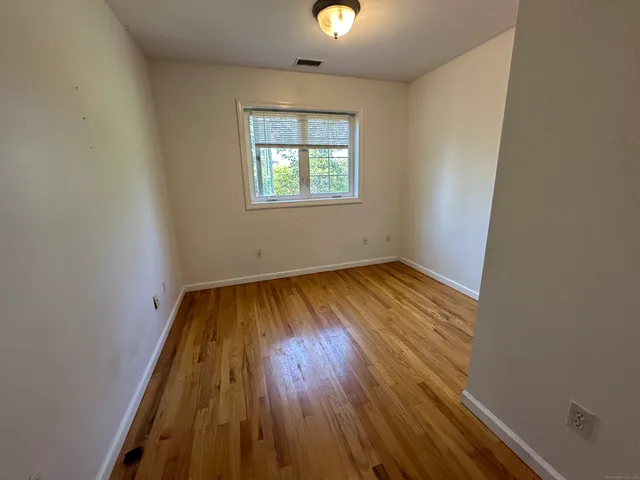 an empty room with wooden floor chandelier and windows