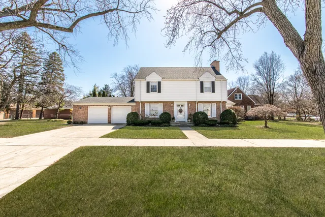 a view of a white house with a big yard and large trees