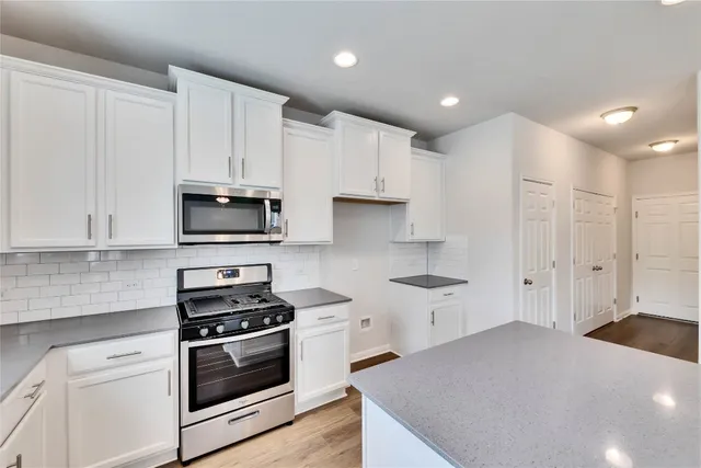 a kitchen with stainless steel appliances white cabinets and a stove top oven