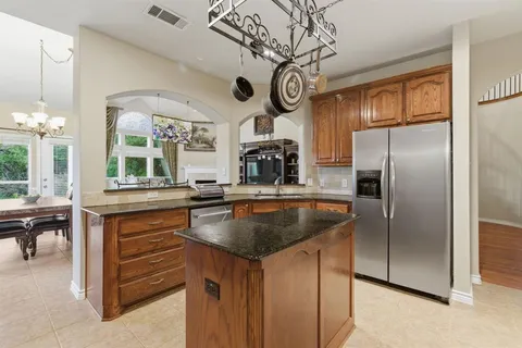 a kitchen with stainless steel appliances granite countertop a sink a oven and a refrigerator with wooden floor