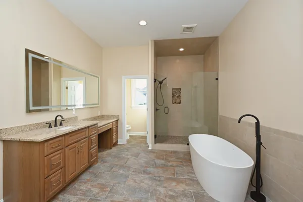 a spacious bathroom with a double vanity sink a mirror a toilet and a bathtub