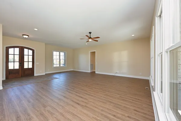an empty room with wooden floor and windows