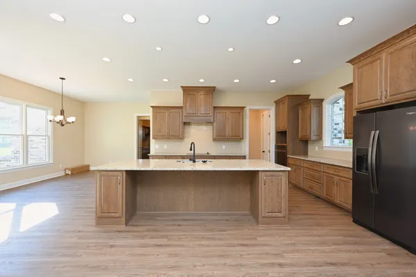 a large kitchen with stainless steel appliances a large counter top a stove and a refrigerator