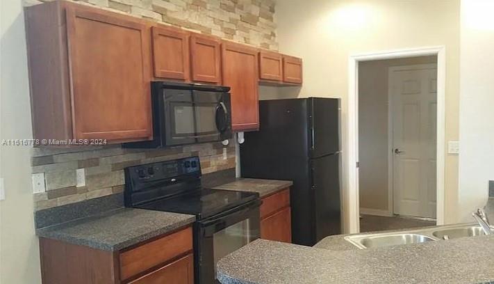 3665 Barred Owl Road Lakeland, FL 33811 - Photo 4 of 7 a kitchen with granite countertop wooden cabinets and a refrigerator
