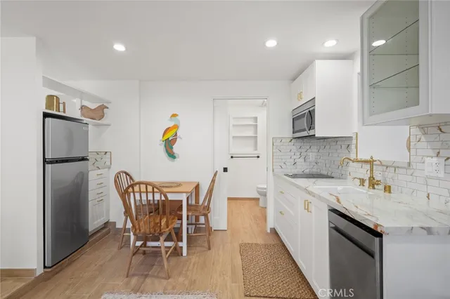 a kitchen with stainless steel appliances granite countertop a sink a stove a refrigerator with a dining table and chairs