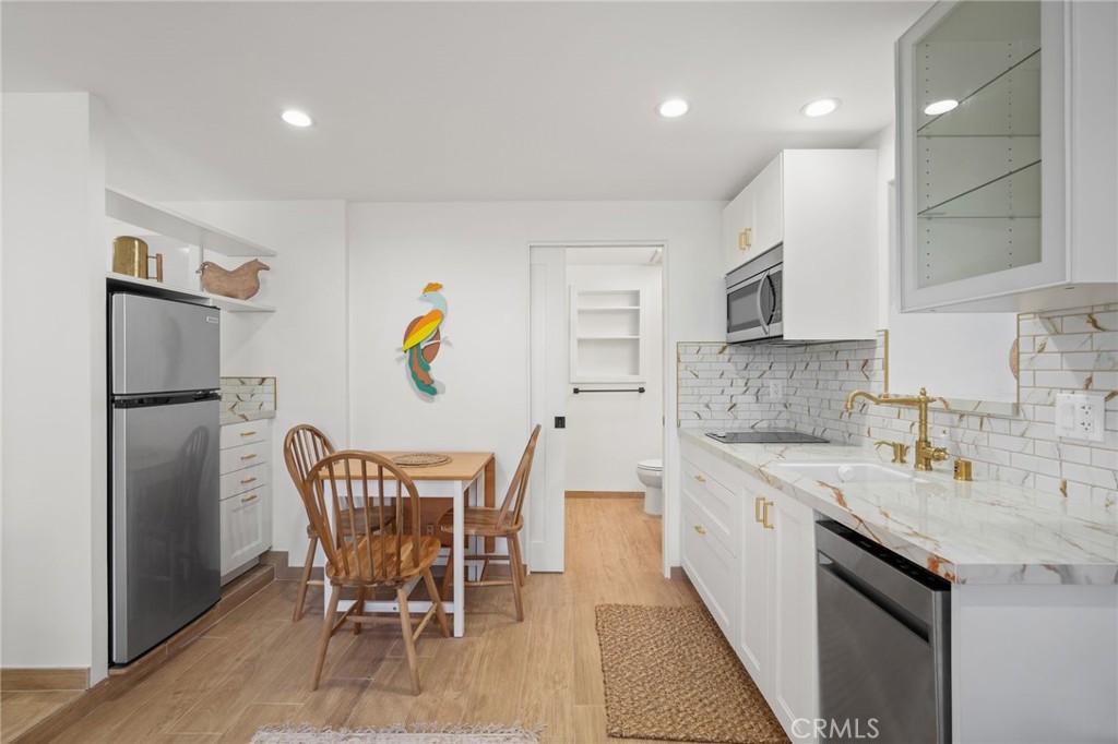 a kitchen with stainless steel appliances granite countertop a sink a stove a refrigerator with a dining table and chairs