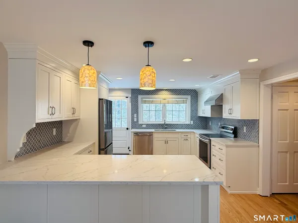 a kitchen with stainless steel appliances granite countertop a sink a stove and a refrigerator