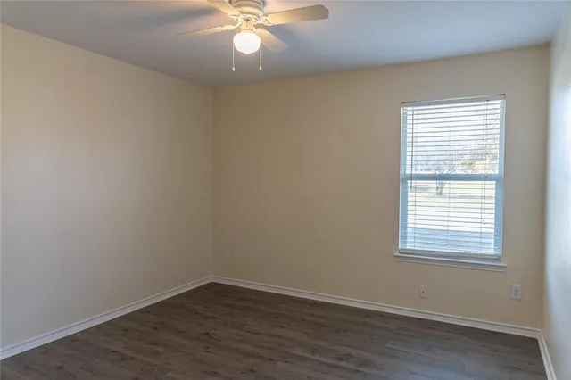a view of an empty room with wooden floor and closet