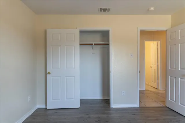 an empty room with wooden floor closet and windows