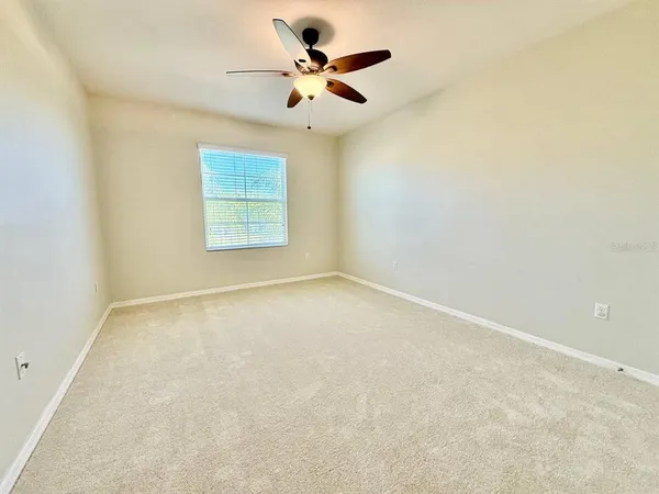 an empty room with a window and a ceiling fan