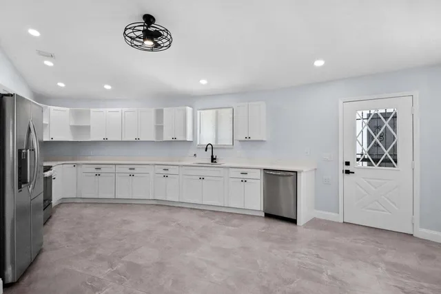 a large white kitchen with a refrigerator a stove top oven a sink and cabinets