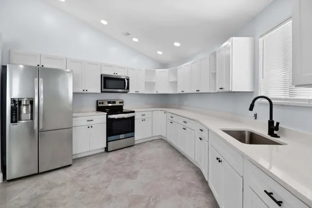 a kitchen with white cabinets and stainless steel appliances
