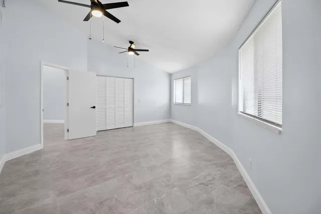 an empty room with windows and fan