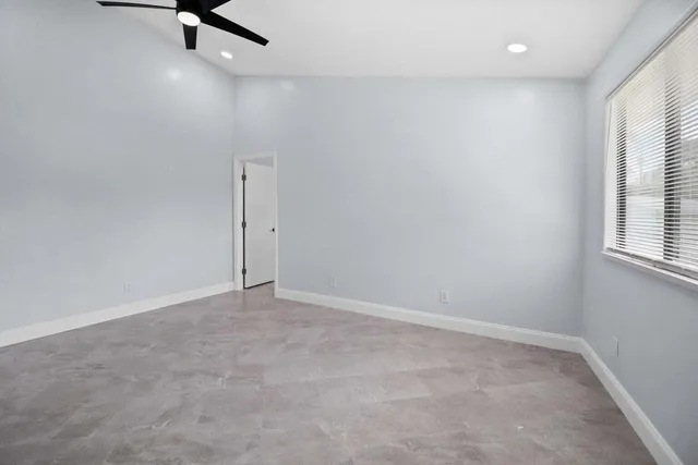 an empty room with windows and fan