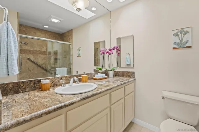 a bathroom with a granite countertop sink a toilet and a mirror