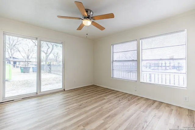 a view of an empty room with wooden floor and a window