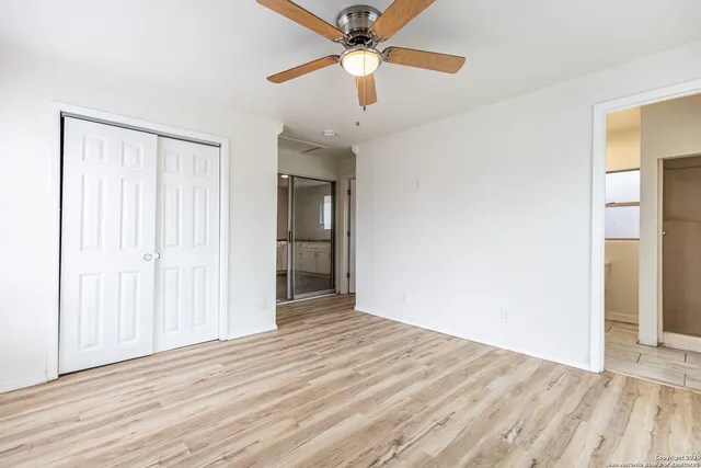 an empty room with wooden floor closet and ceiling fan
