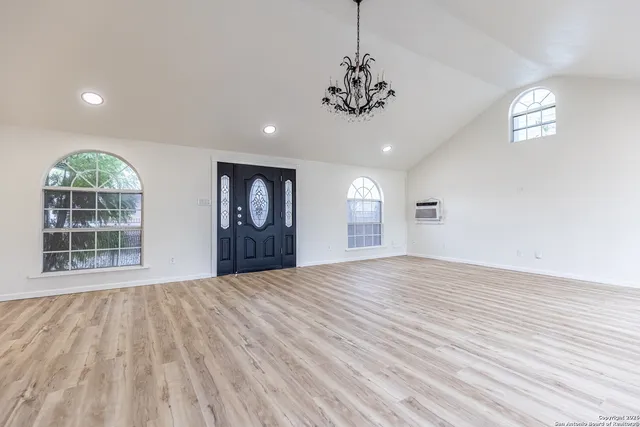 a view of an empty room with a window and wooden floor