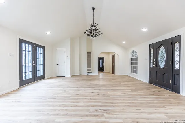 a view of a livingroom with a chandelier fan and wooden floor