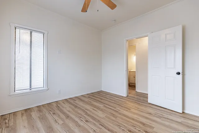 an empty room with wooden floor cabinet and windows