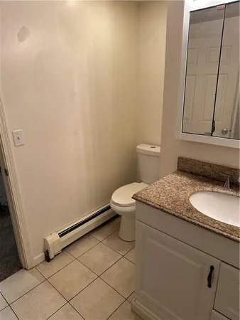 a bathroom with a granite countertop sink and a toilet