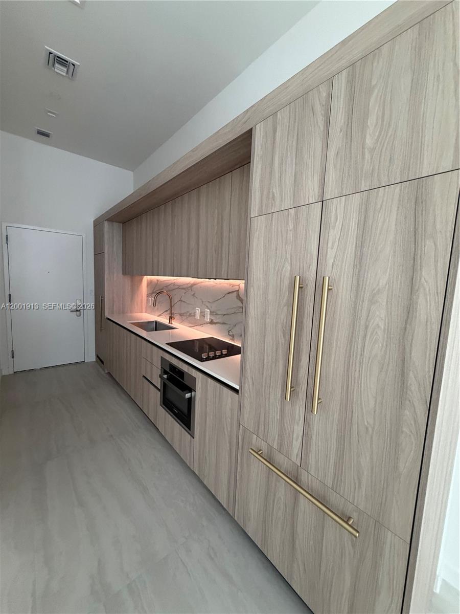 77 Southeast 5th Street, Unit 1007 Miami, FL 33131 - Photo 3 of 31 a kitchen with stainless steel appliances a refrigerator and a stove