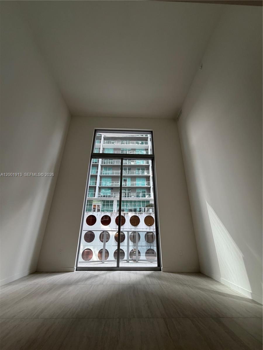 77 Southeast 5th Street, Unit 1007 Miami, FL 33131 - Photo 8 of 31 a view of an empty room with window and brick wall