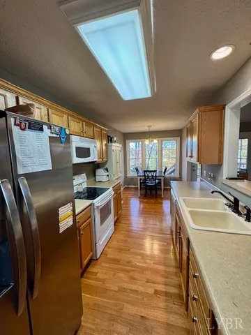 a kitchen with stainless steel appliances granite countertop a refrigerator a stove and a sink with couches next to a large window