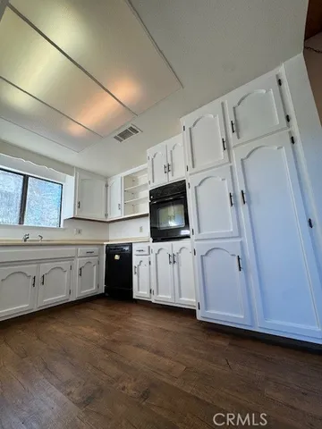 a large white kitchen with white cabinets and wooden floor