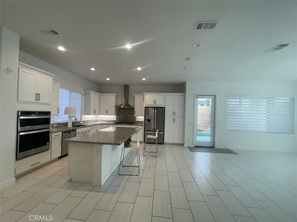 170 Episode Irvine, CA 92618 - Photo 8 of 63 a kitchen with stainless steel appliances kitchen island granite countertop a stove top oven a sink dishwasher and a refrigerator with wooden floor