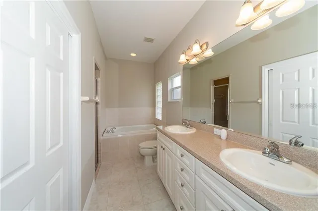 a bathroom with a double vanity sink toilet mirror and shower