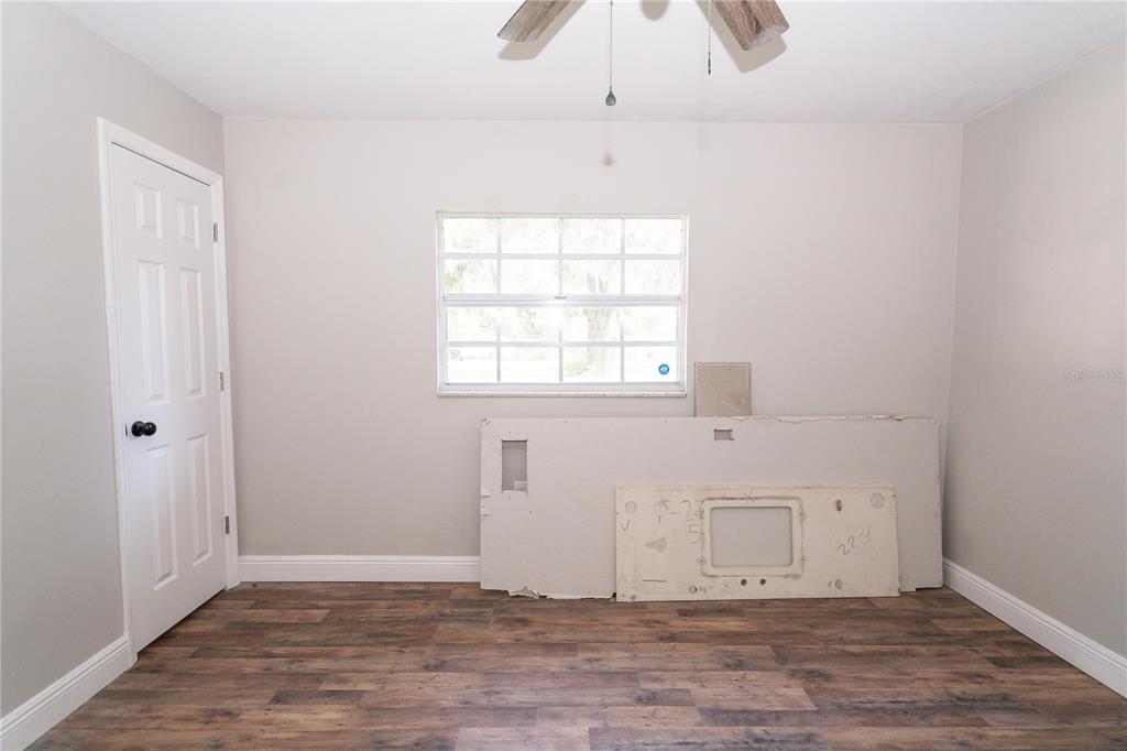 3102 Williams Road Brandon, FL 33510 - Photo 25 of 29 an empty room with wooden floor chandelier fan and windows