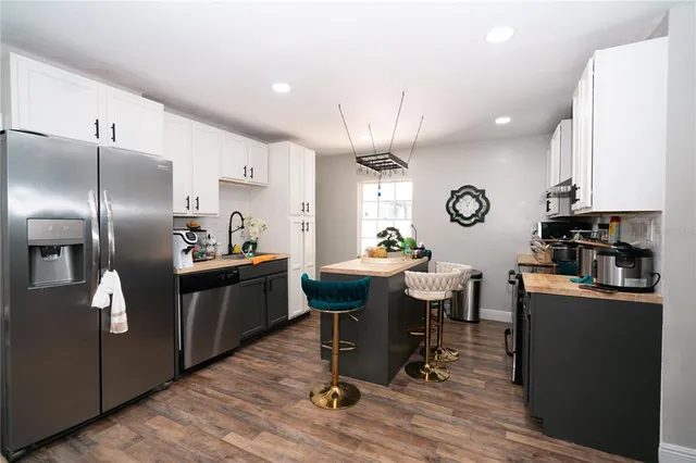 a kitchen with kitchen island granite countertop a sink cabinets and stainless steel appliances