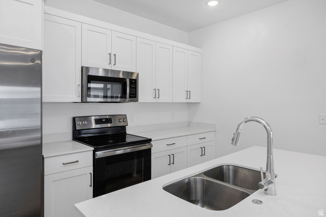 3115 South 200 West, Unit C201 Nibley, UT 84321 - Photo 4 of 23 Kitchen featuring white shaker cabinetry, stainless steel appliances, light-toned countertops, a dual basin stainless steel sink, and a chrome pull-down faucet