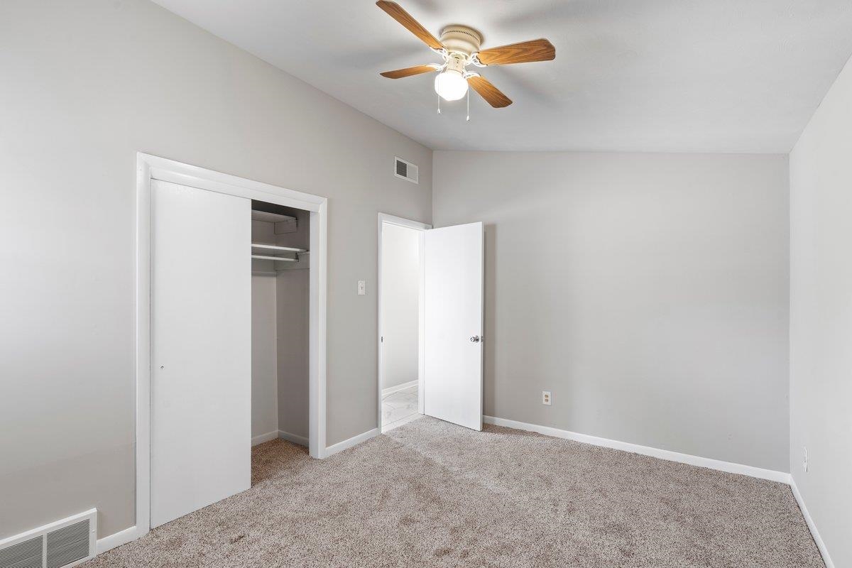 4948 Knight Arnold Road Memphis, TN 38118 - Photo 13 of 27 Unfurnished bedroom featuring vaulted ceiling, light carpet, ceiling fan, and a closet