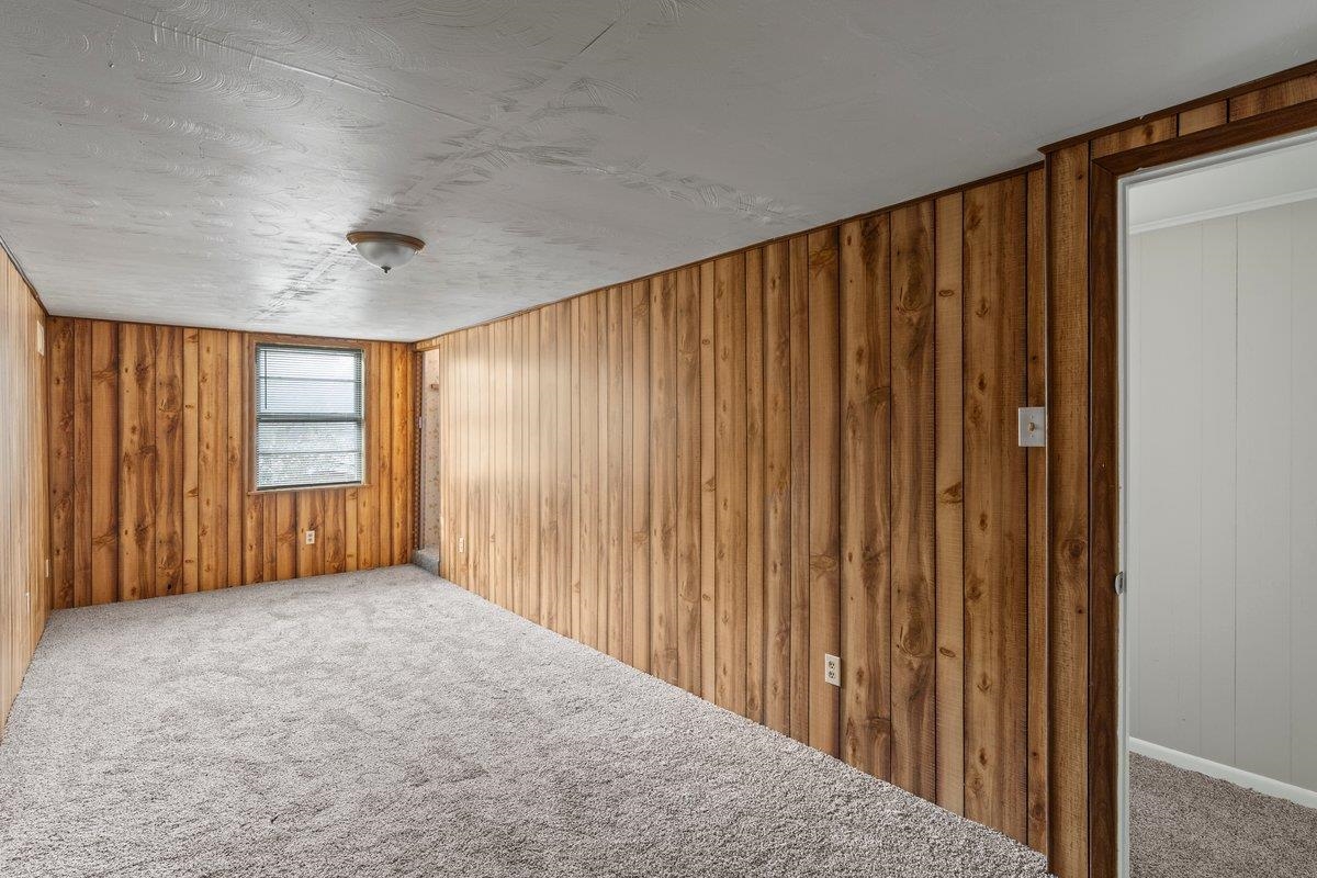 4948 Knight Arnold Road Memphis, TN 38118 - Photo 17 of 27 Carpeted spare room featuring wood walls